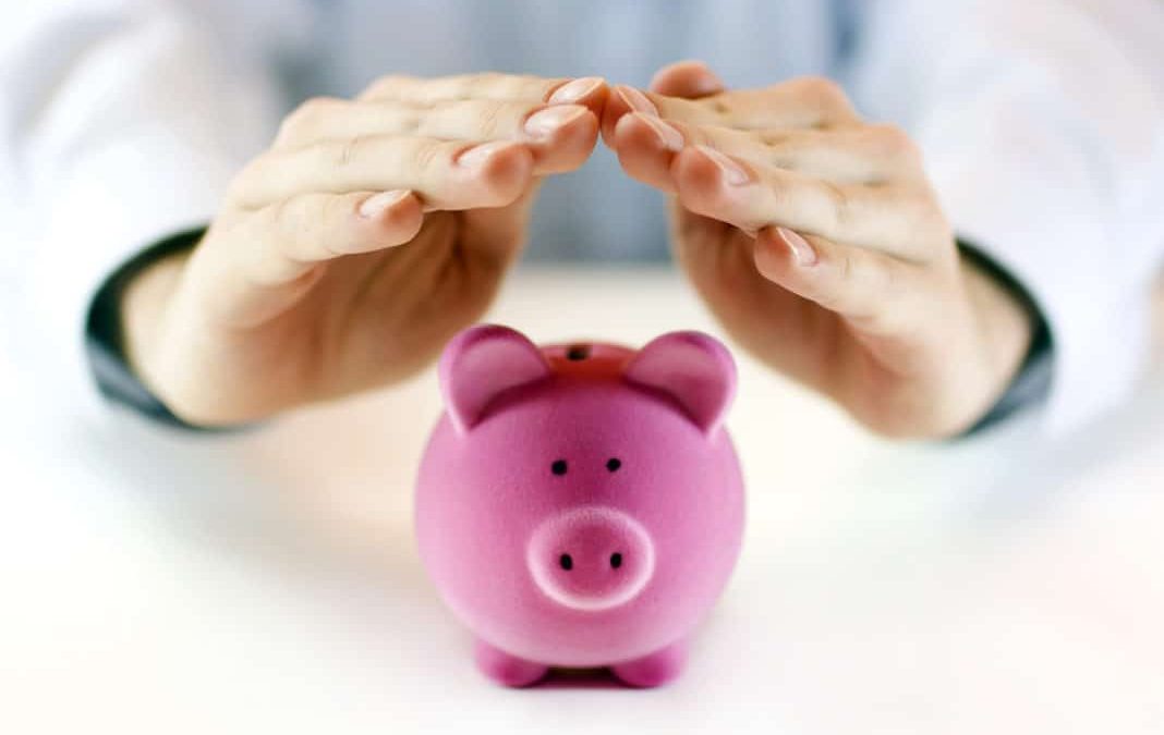 A hand protecting a piggy coin bank representing JobKeeper